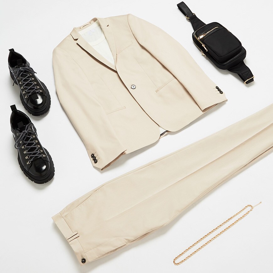 A flat lay wedding outfit of a cream suit with a T-shirt and matching accessories. Available at ASOS.