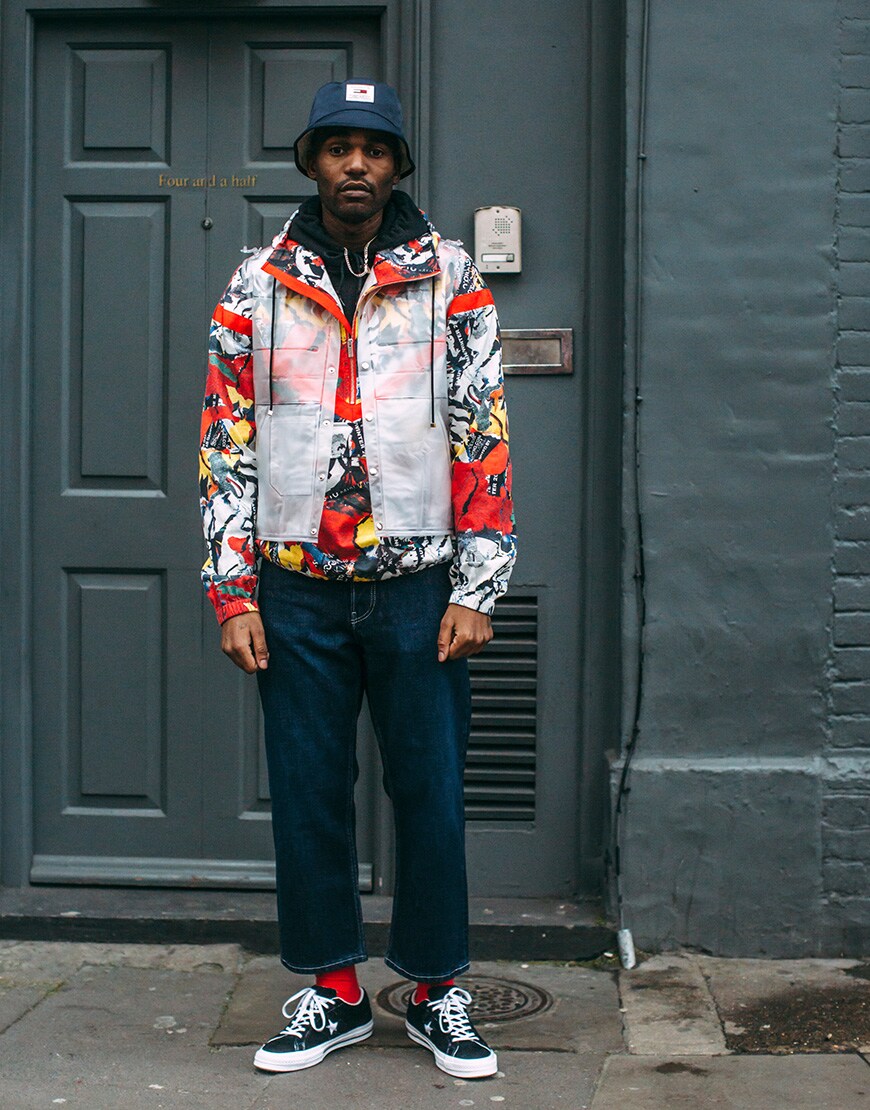 A picture of a street style wearing a bright jacket and a bucket hat.