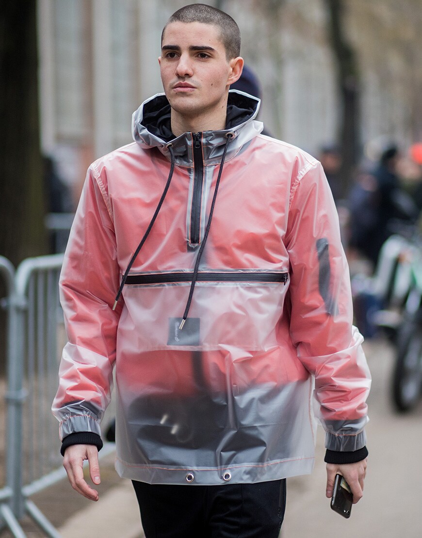 A picture of a street styler wearing a translucent rain jacket and an orange bomber jacket.