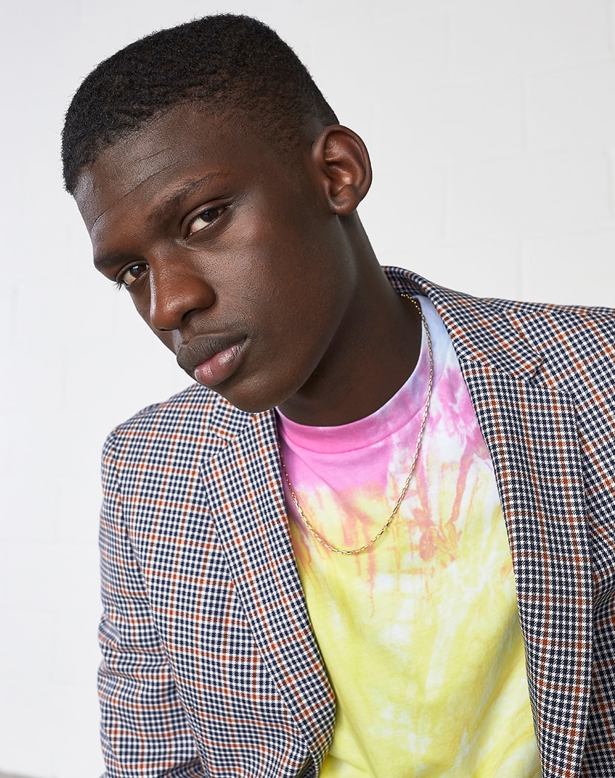 A picture of a model wearing a check blazer and a tie-dye T-shirt.