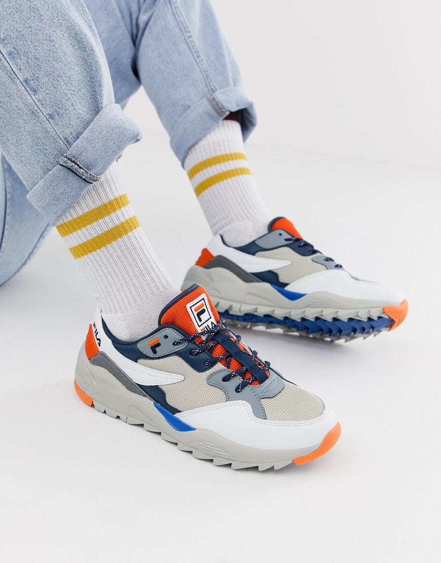 A picture of a model wearing a pair of chunky, colourful trainers from Fila. Available at ASOS.