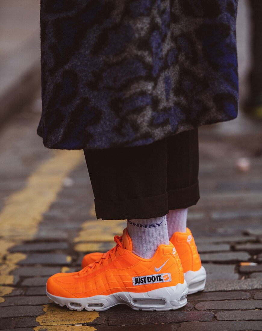 A picture of a pair of Nike Air 95 trainers in a neon-orange colourway.