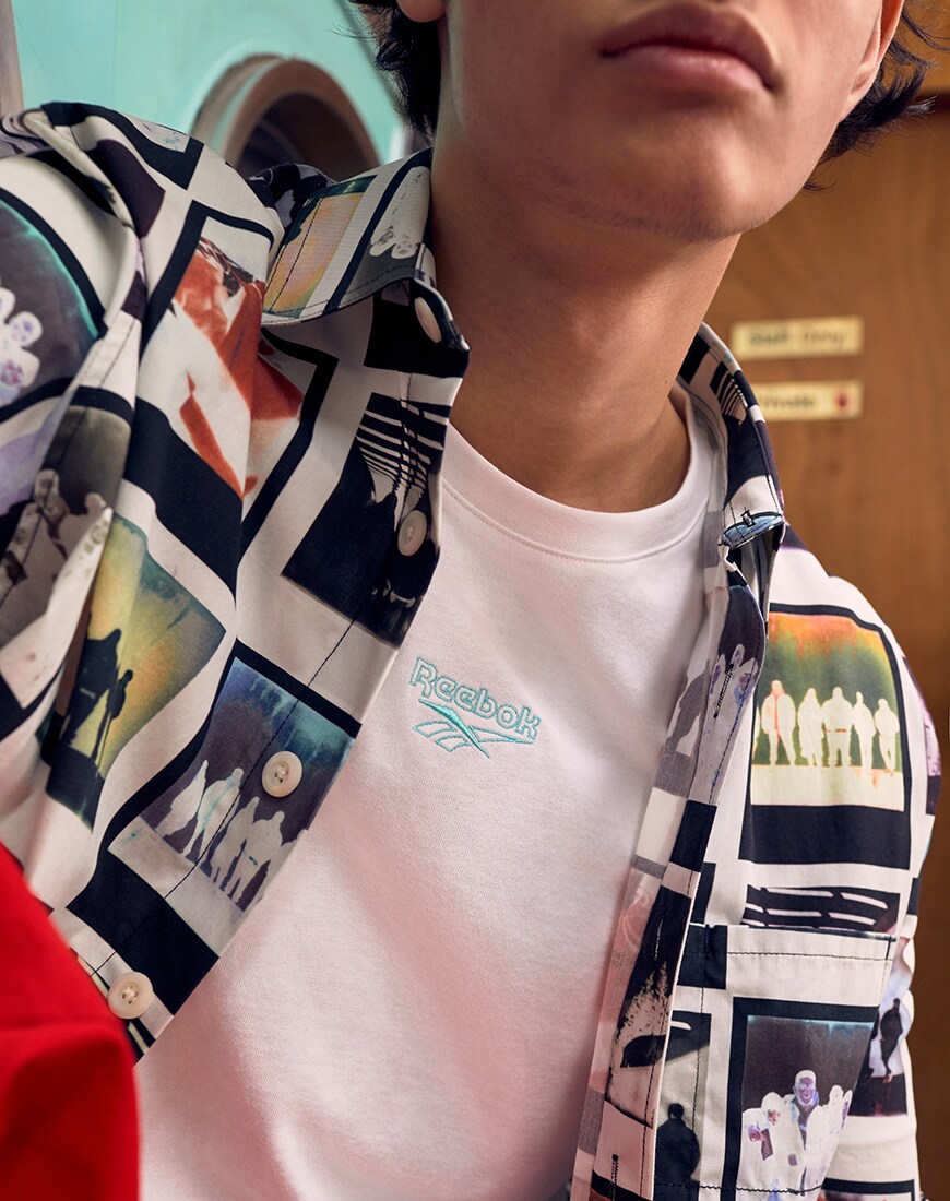 Une image d'un modèle portant une chemise imprimée et un t-shirt Reebok. Disponible chez ASOS.
