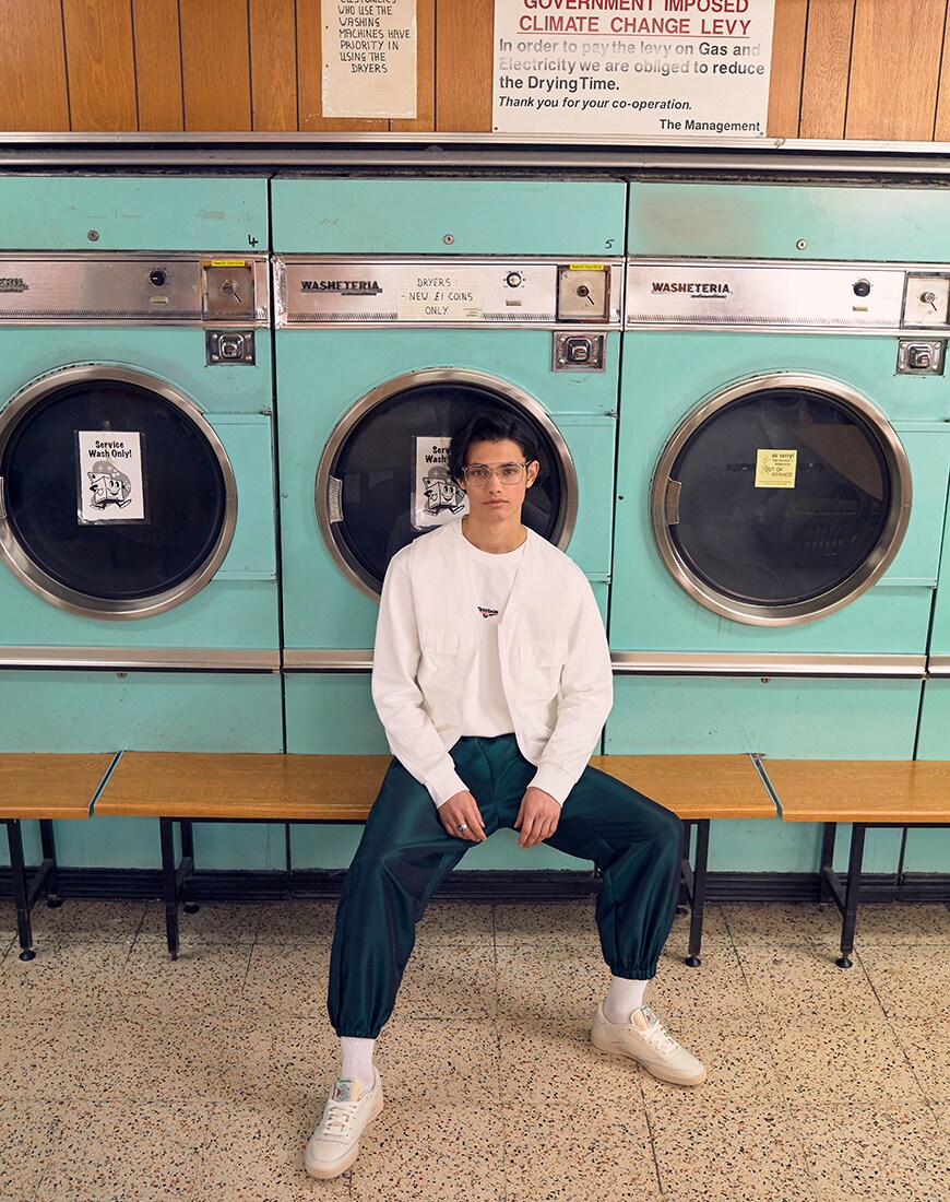 Une image d'un modèle portant un t-shirt Reebok et des baskets avec une chemise de style utilitaire et un jogging. Disponible chez ASOS.