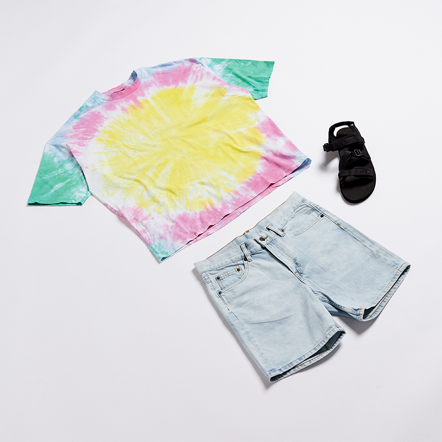 A picture of flat lay outfit including a tie-dye T-shirt, light-wash denim shorts and techy sandals. Available at ASOS.