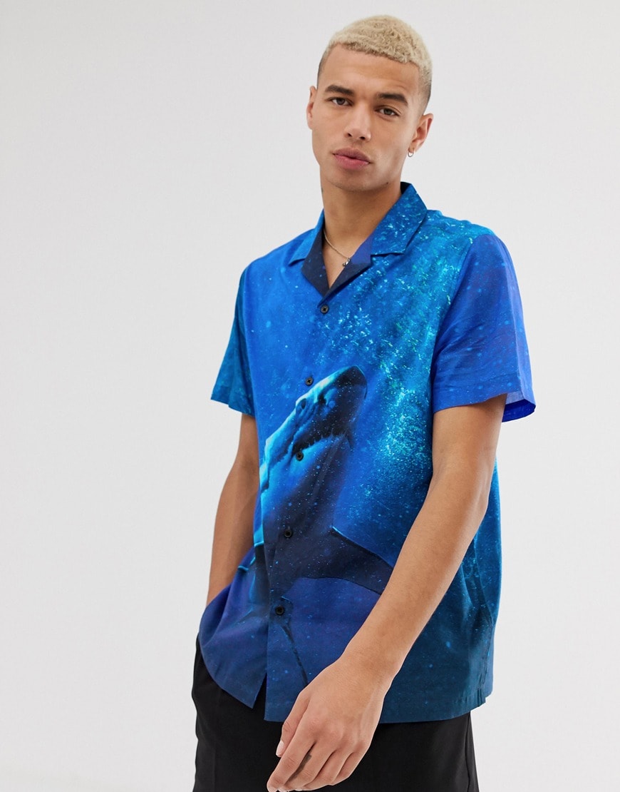 A picture of a model wearing a blue shirt featuring a photographic shark print.