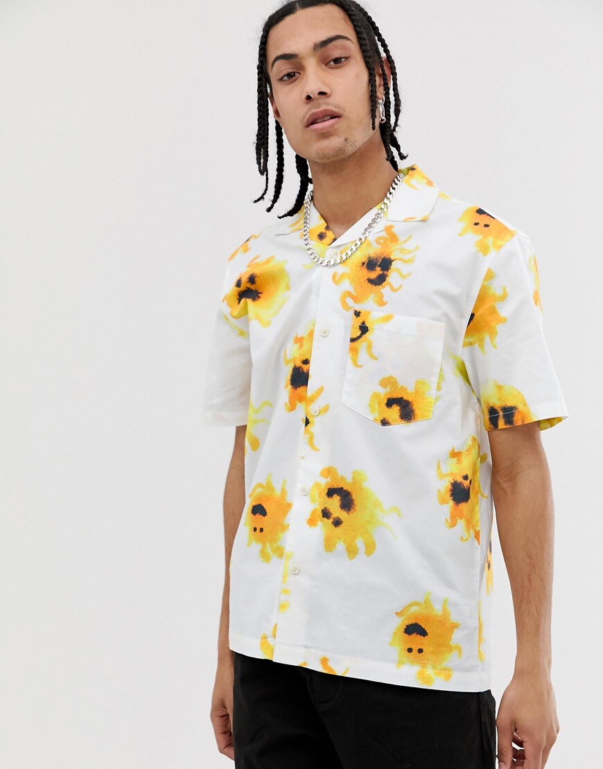 A picture of a model wearing a revere collar shirt by Weekday featuring an all-over sun print. Available at ASOS.