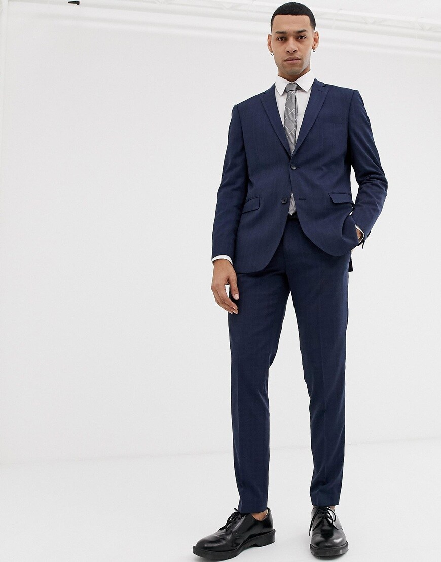 A picture of a model wearing a navy suit with black shoes. Available at ASOS.