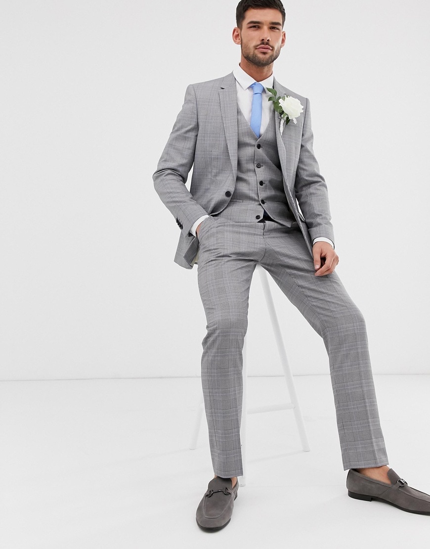 A picture of a model wearing a grey check, three-piece suit with dark grey loafers. Available at ASOS.
