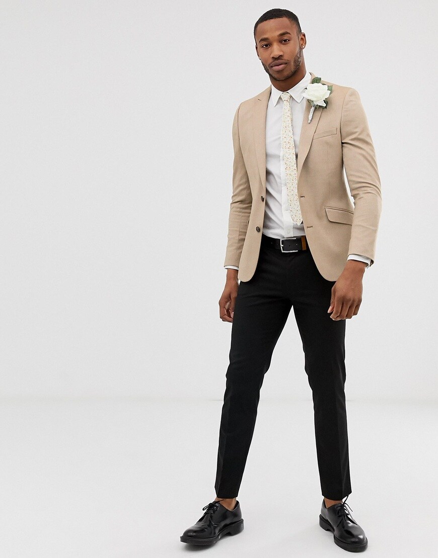 A picture of a model wearing a beige blazer with black trousers and patent black shoes. Available at ASOS.