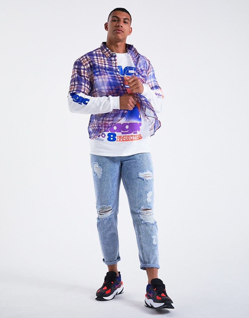 Image d'un modèle portant une chemise à carreaux transparente par-dessus un t-shirt imprimé à manches longues avec un jean déchiré et des baskets Nike. Disponible chez ASOS.