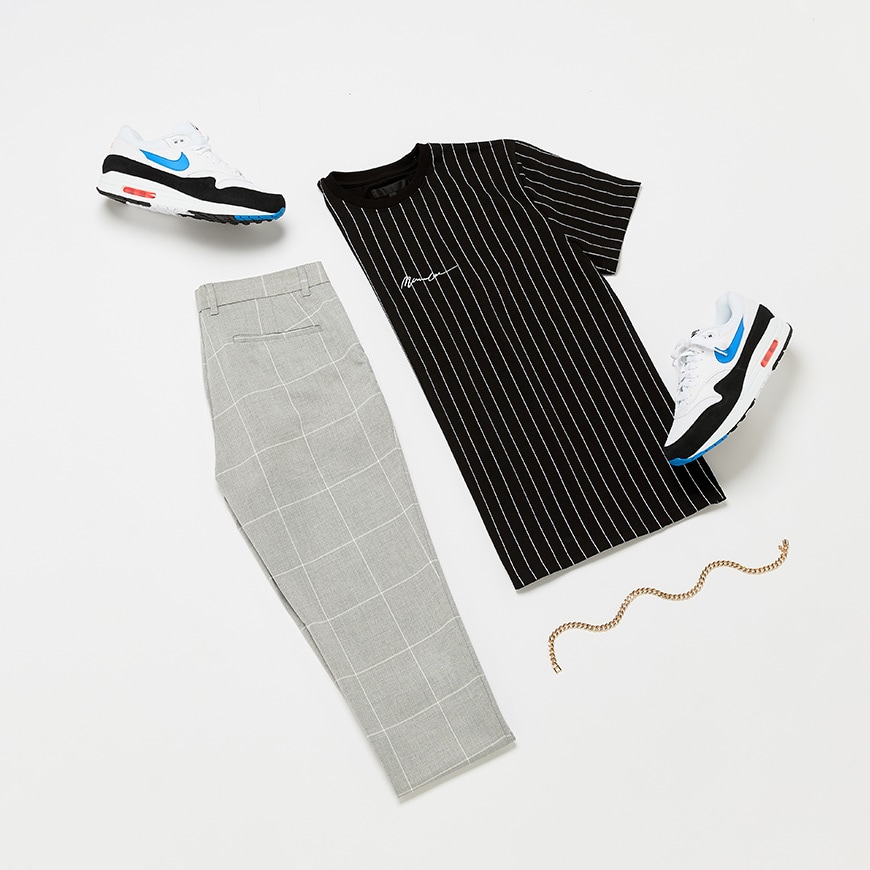 A picture of a flat lay outfit featuring a pin-stripe T-shirt, check trousers, Nike Air Max trainers and a chain necklace. Available at ASOS.