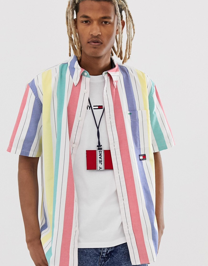A picture of a model wearing a striped shirt from the Tommy Jeans Heritage Summer Capsule collection. Available at ASOS.