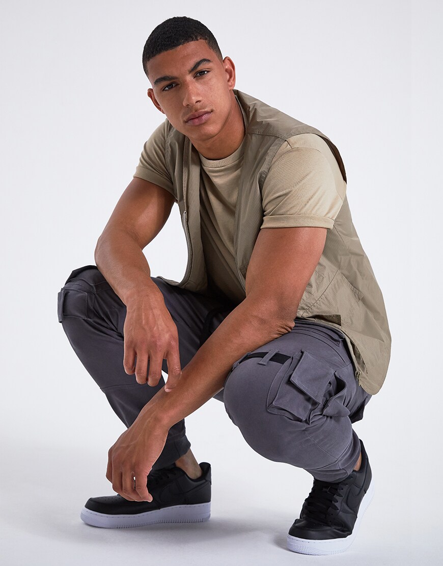 A picture of a model wearing a khaki T-shirt, a utility-style gilet and cargo trousers. Available at ASOS