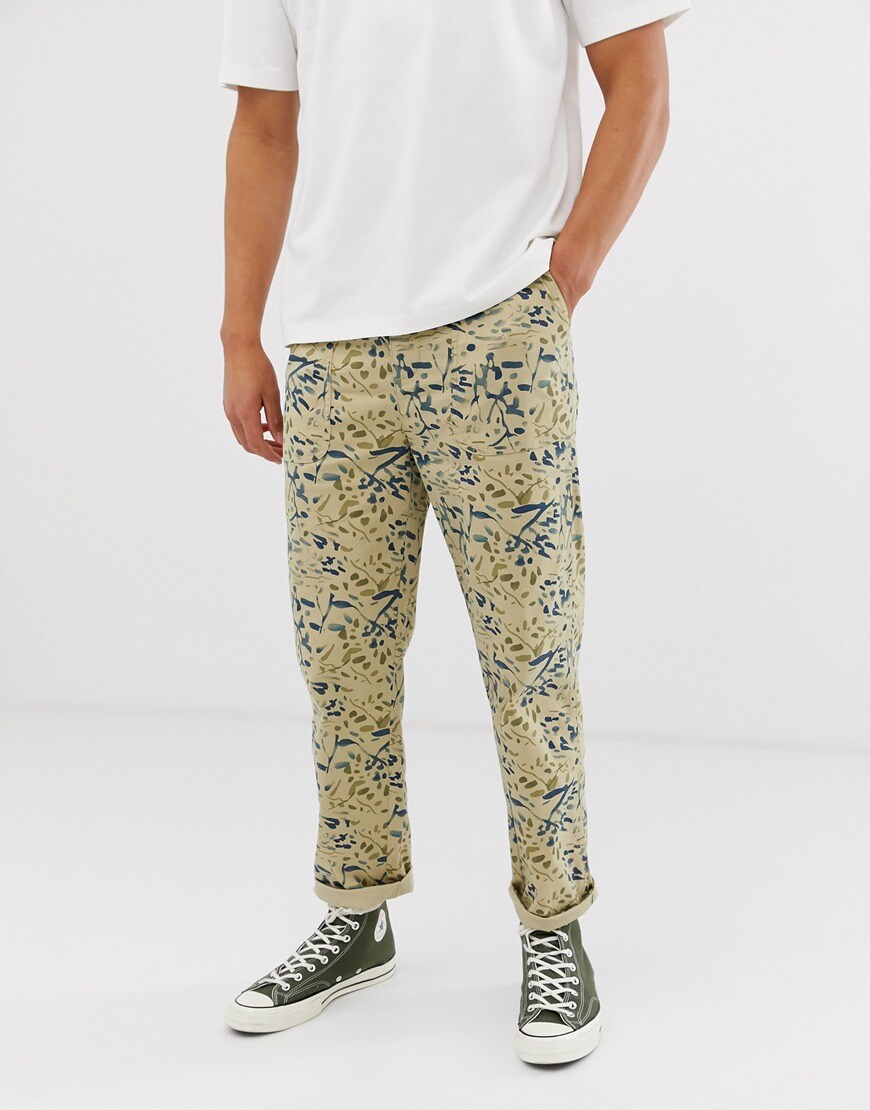 A picture of a model wearing utility trousers with a watercolour print by ASOS DESIGN.