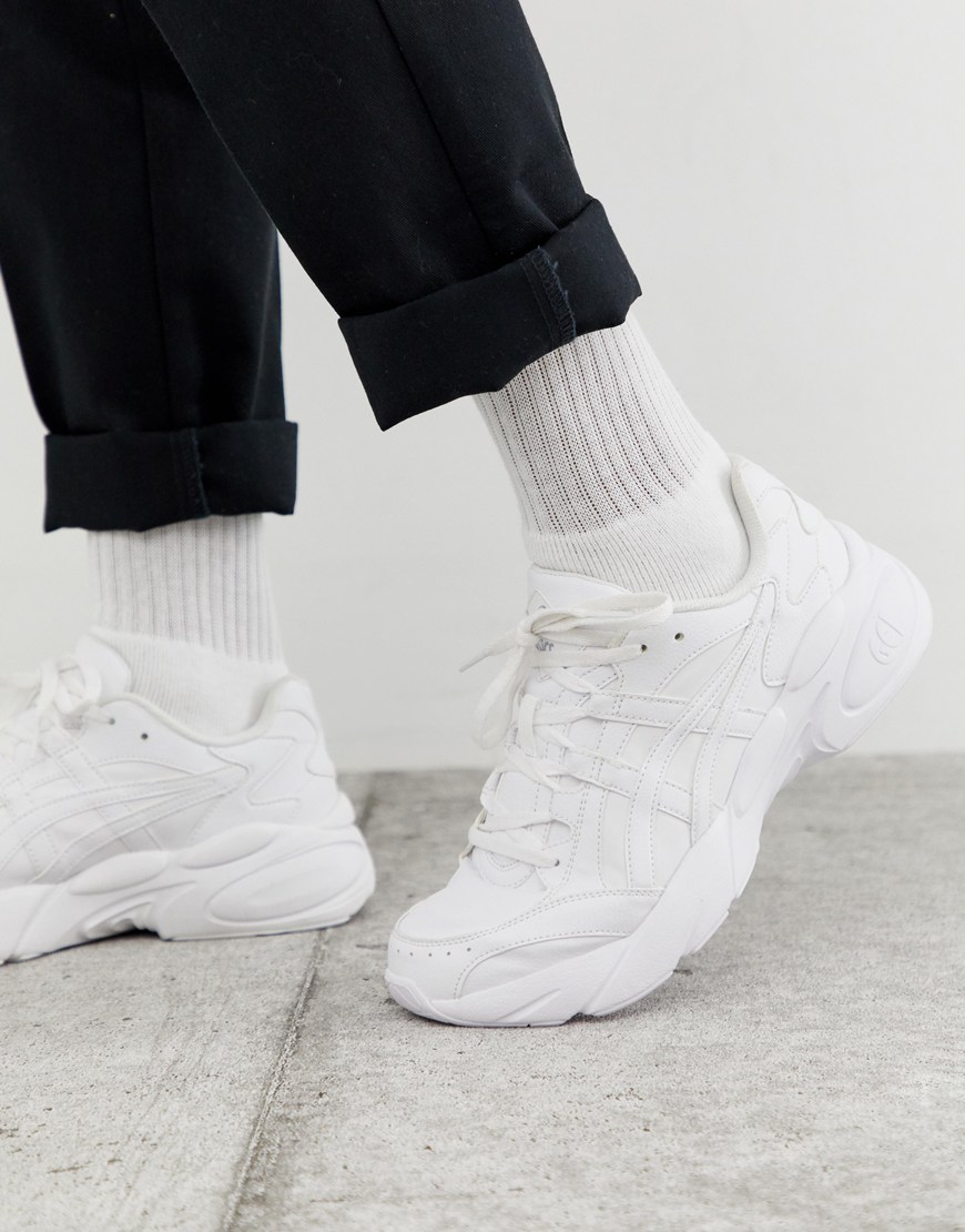 A picture of a model wearing a pair of triple white Asics Bondi trainers. Available at ASOS.
