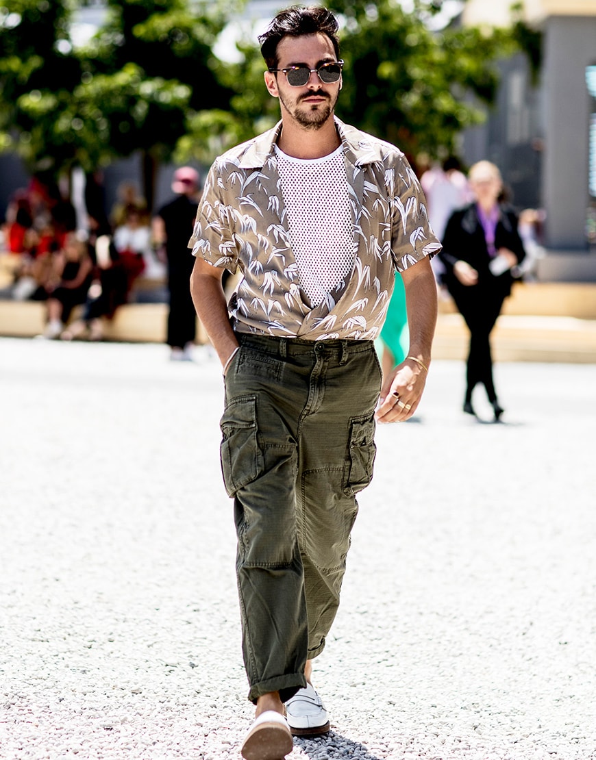 A picture of a man wearing a palm-print shirt, utility trousers and loafers.