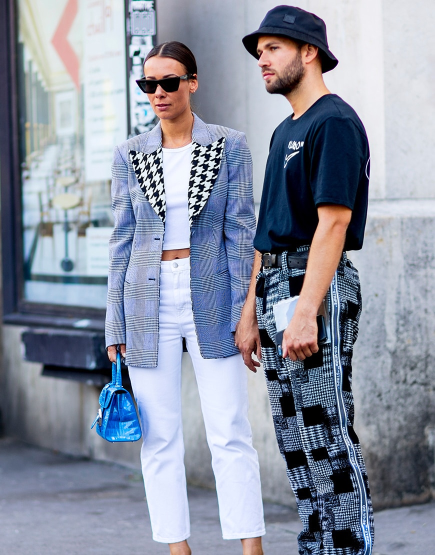 A picture of a man wearing a bucket hat, T-shirt and printed trousers.
