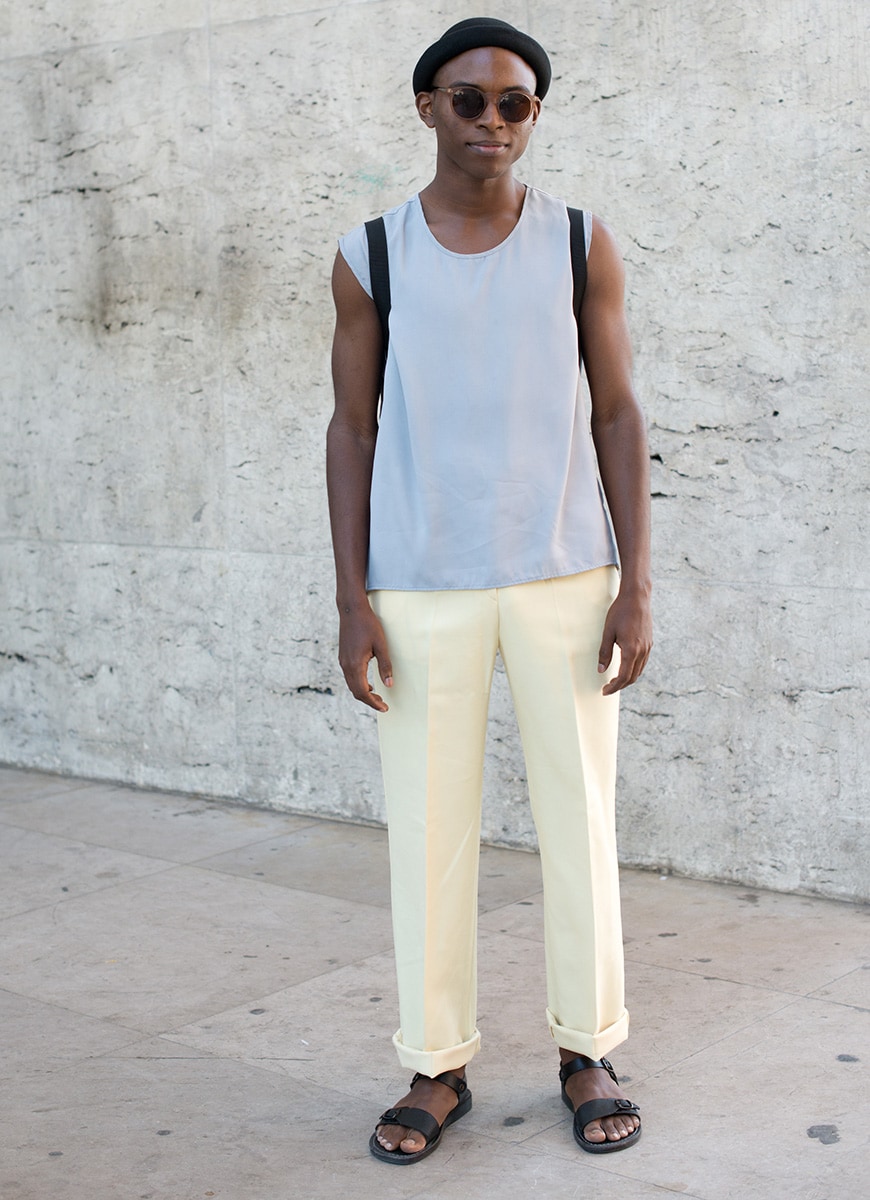 A picture of a man wearing a sleeveless T-shirt, wide-cut trousers and sandals.