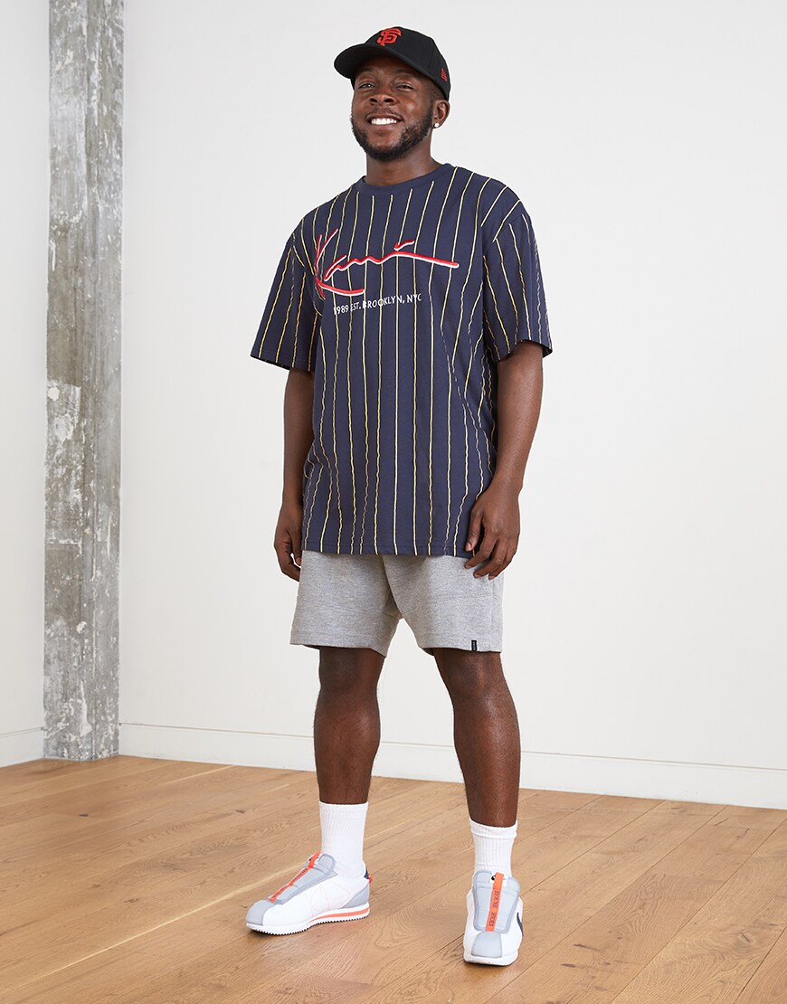 A picture of an ASOSer wearing a Karl Kani T-shirt and grey shorts. Available at ASOS.