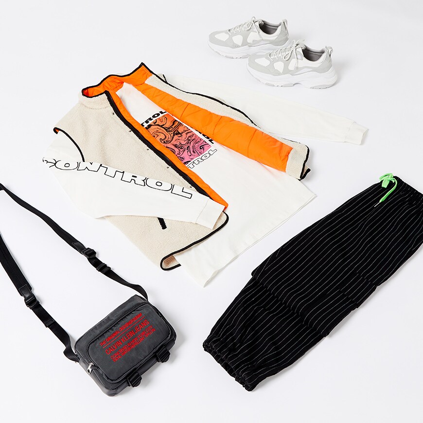 A flat-lay image of a transitional look including a borg gilet, a long-sleeve printed T-shirt, pin-stripe cargo trousers and accessories. Available at ASOS.