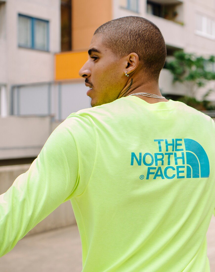 A picture of a man wearing a neon green long sleeve t-shirt from The North Face