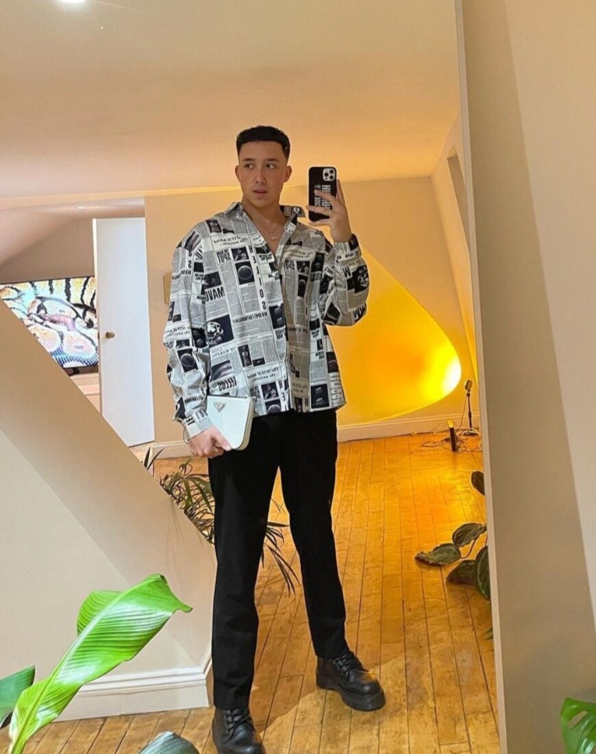 @kyron.hamilton taking a mirror selfie in a newspaper-printed shirt and black trousers | ASOS Style Feed 