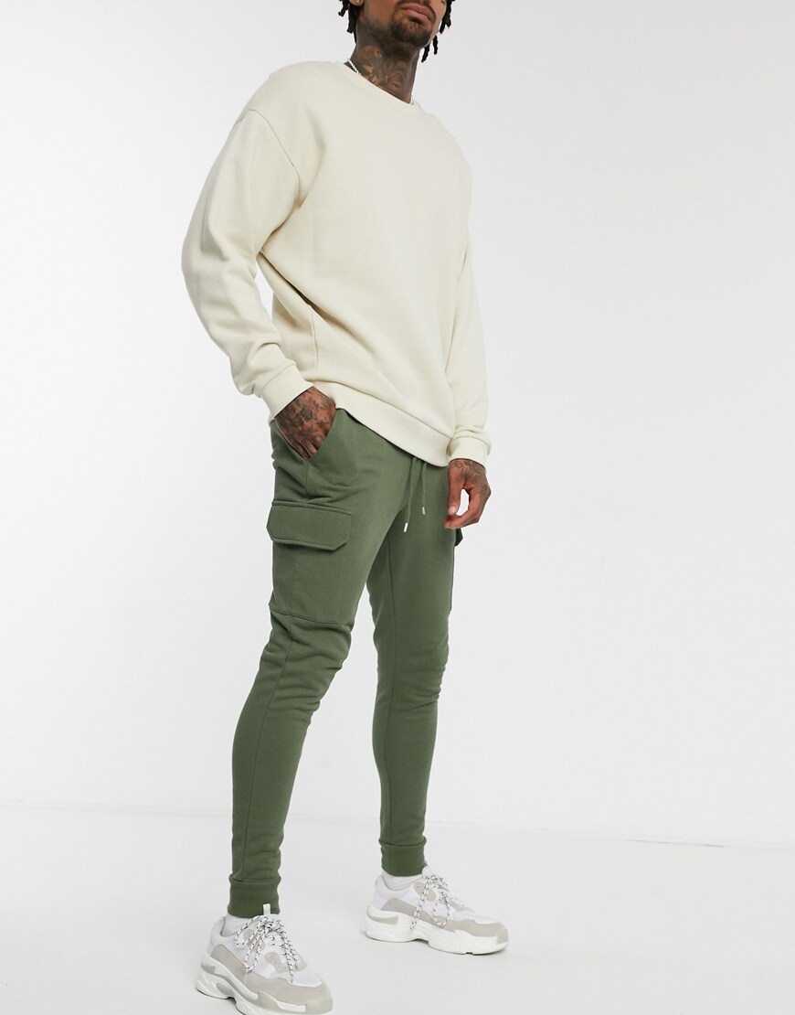 A picture of a model wearing an off-white sweatshirt and skinny cargo joggers by ASOS DESIGN. Available at ASOS.