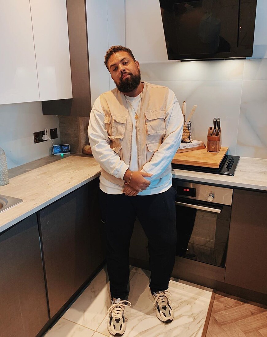 A picture of a man wearing a long-sleeve T-shirt, a utility gilet, black joggers and chunky trainers. Available at ASOS.
