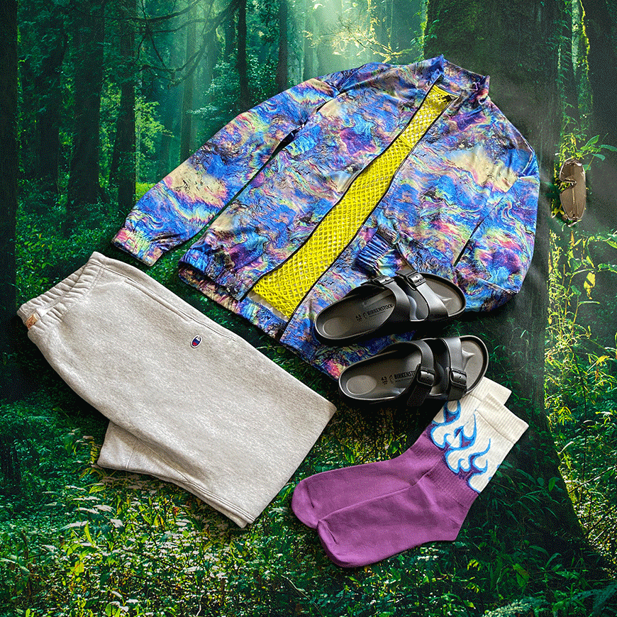 A moving gif of a festival outfit against a changing background of forest, desert and bright-blue skies. The outfit features a multicoloured track jacket, bright-yellow vest, grey Champion joggers, black Birkenstock sandals and purple-flame-print socks. All available at ASOS.