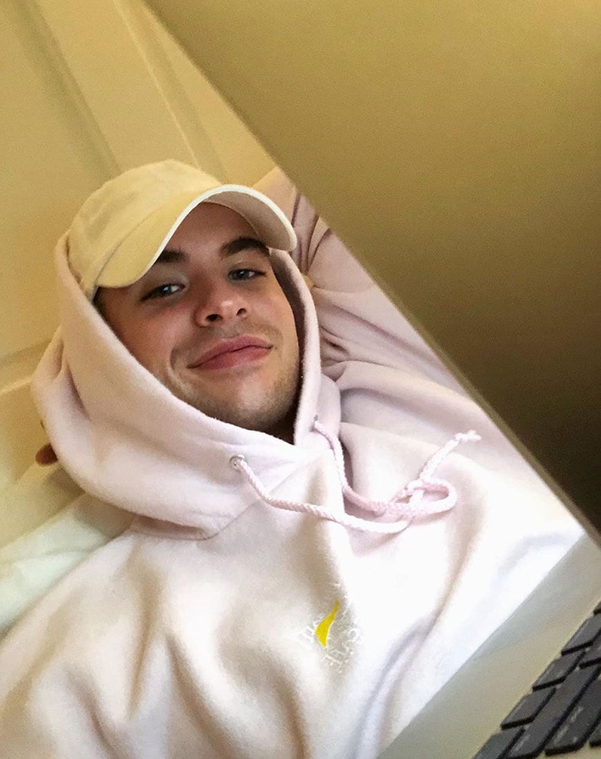 A picture of an ASOS Insider, asos_aaron at home wearing a pale pink hoodie and a cap. Available at ASOS.