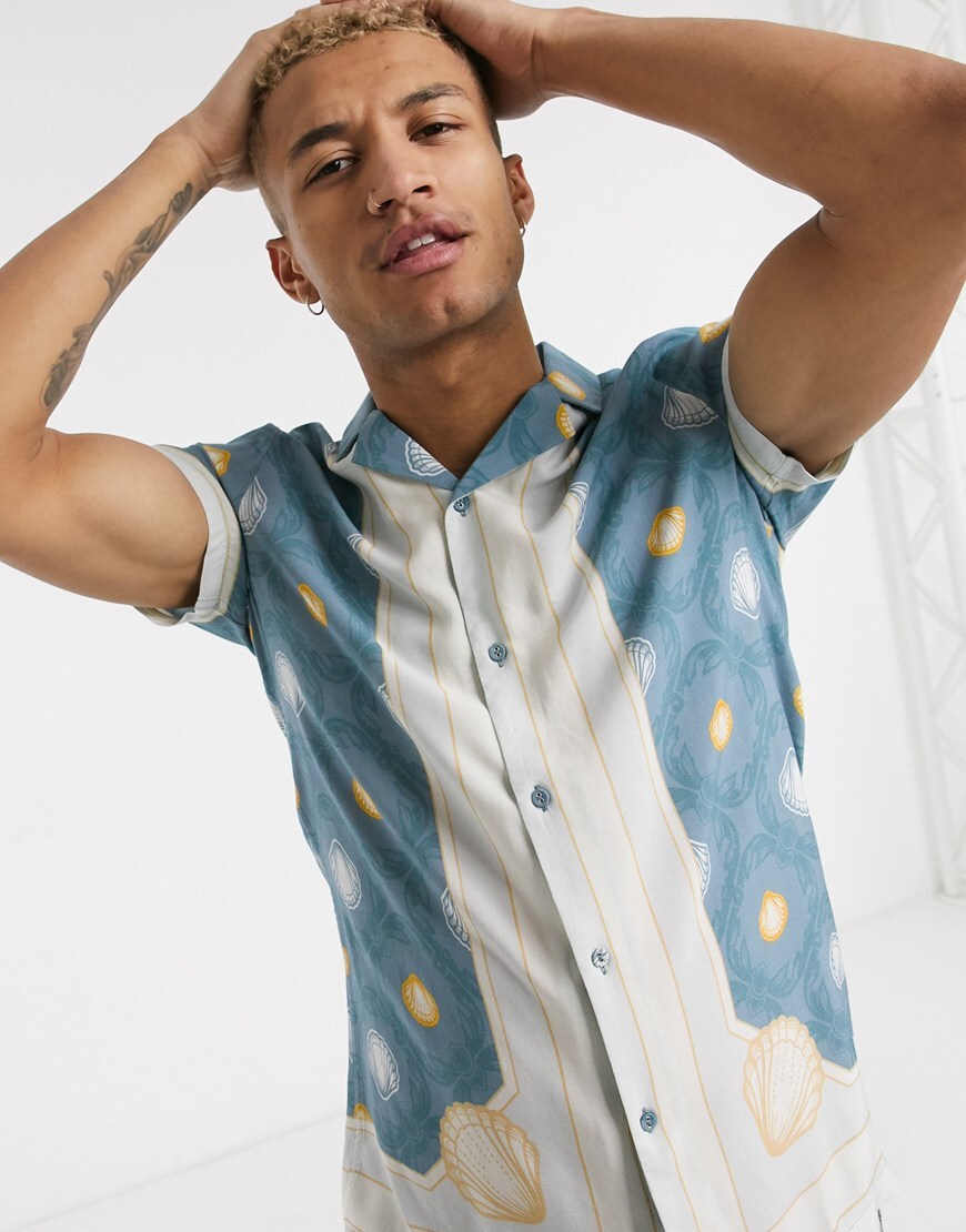 A picture of a model wearing a blue, white and yellow printed shirt featuring a floral border print. Part of the Responsible edit on ASOS.
