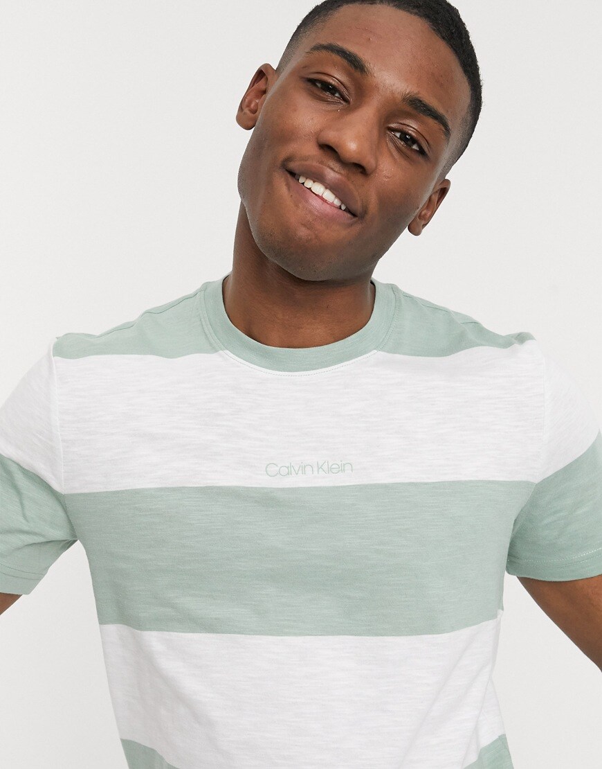 A picture of a model wearing a green and white striped T-shirt by Calvin Klein with an embroidered logo on the chest. Part of the ASOS Responsible Edit, available now.