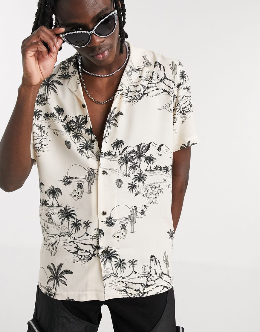 A picture of a printed shirt from the ASOS Responsible edit, with a beige cap and round sunglasses. Available at ASOS.