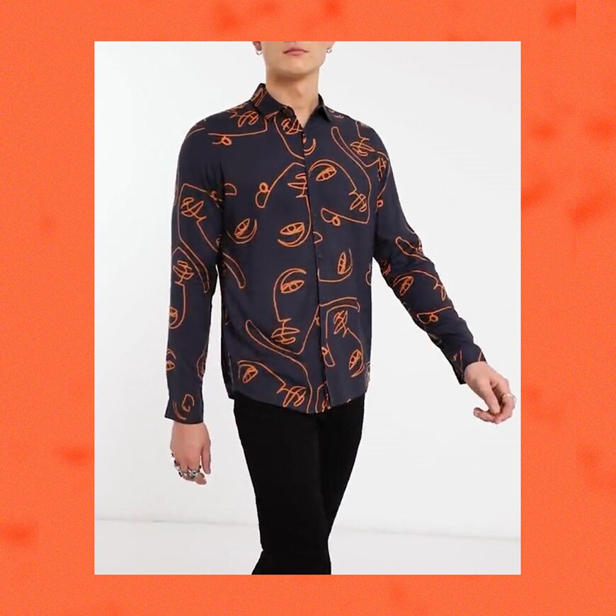 A picture of a model wearing a navy shirt featuring an all-over scribble face print in orange. One of ASOS' five best date-night shirts. Available now.