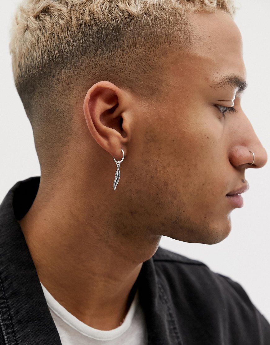 A picture of a model wearing a silver-tone earring featuring a feather pendant. Available at ASOS.