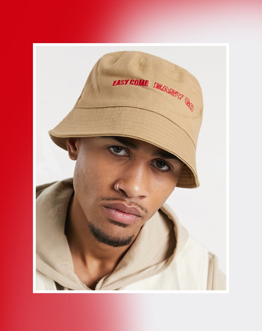 A picture of a model wearing a tan bucket hat with an embroidered logo on the front. Available at ASOS | ASOS Style Feed