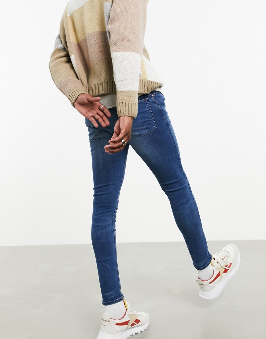 A picture of a model wearing a pair of dark-blue spray-on skinny jeans from the new ASOS DESIGN sustainable denim collection | ASOS Style Feed
