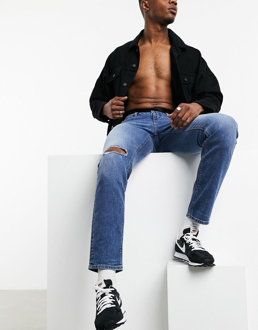 A picture of a model wearing a pair of mid-wash blue slim jeans from the new ASOS DESIGN sustainable denim collection | ASOS Style Feed