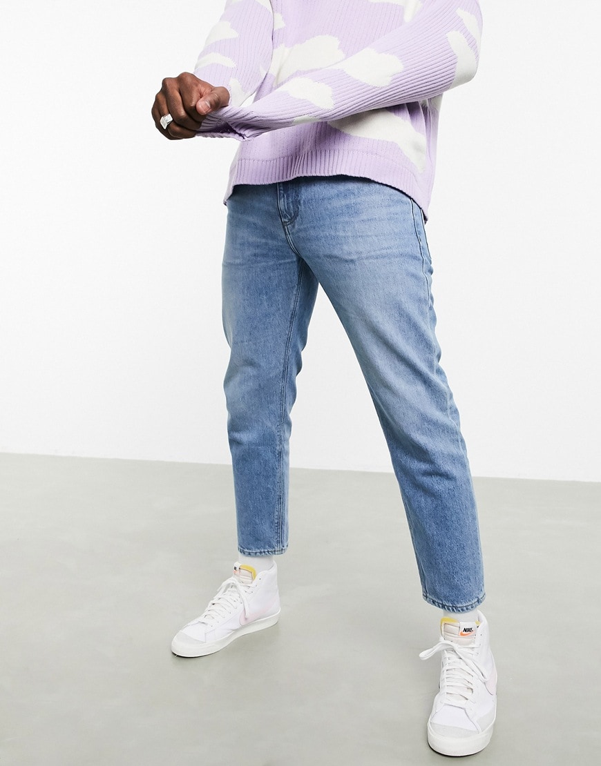 A picture of a model wearing a pair of light-wash blue jeans from the ASOS DESIGN sustainable denim collection. Available at ASOS | ASOS Style Feed