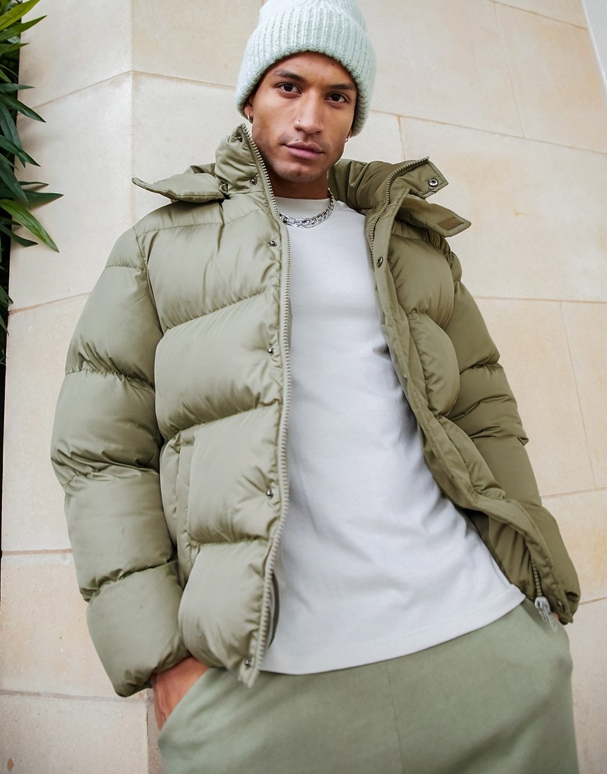 Model wearing ASOS DESIGN sustainable puffer jacket with detachable hood in khaki