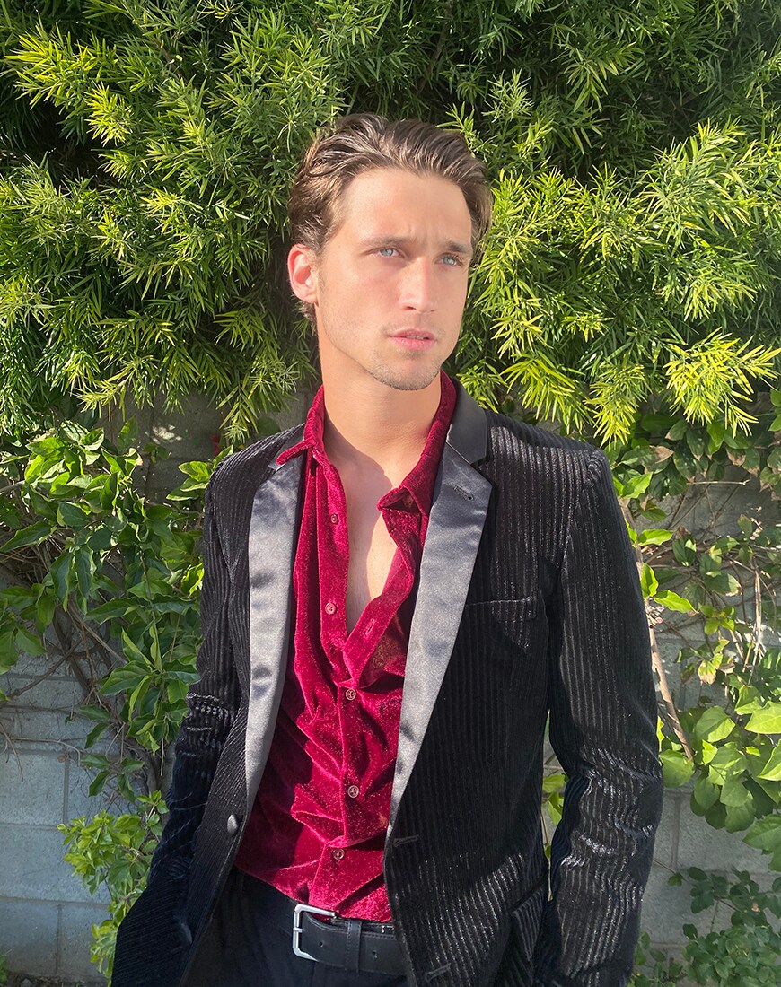 Christian Vierling standing in a black suit jacket and satin red shirt, looking to the side| ASOS Style Feed