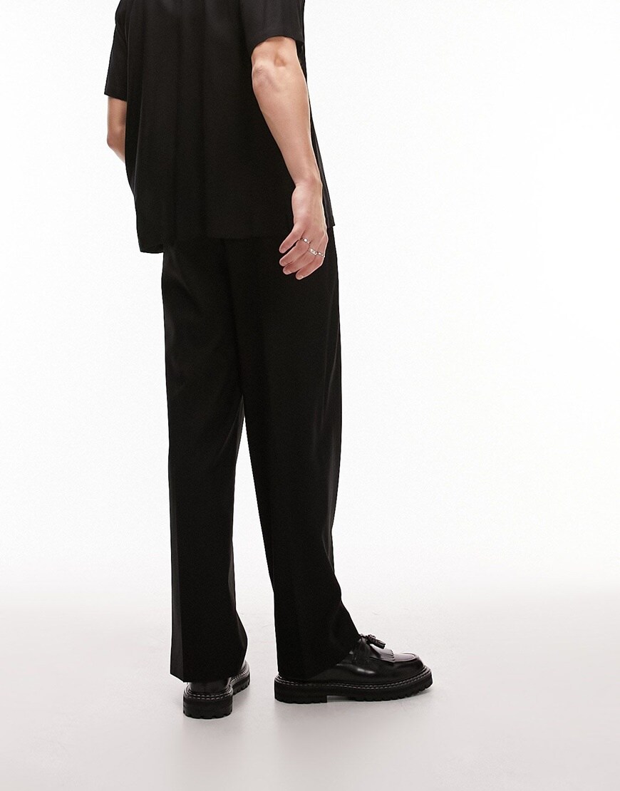 Model wearing relaxed black trousers 