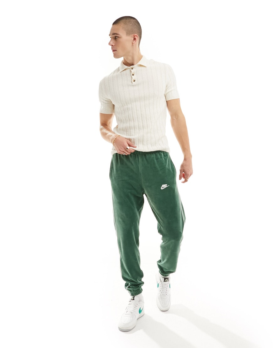 Model wearing a knitted polo and velour joggers