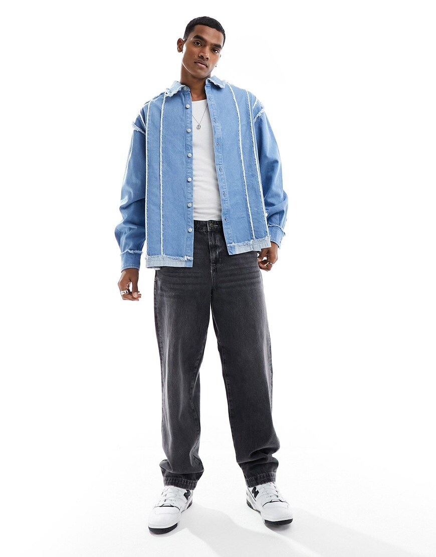 Man wearing distressed blue denim oversized shirt with black jeans