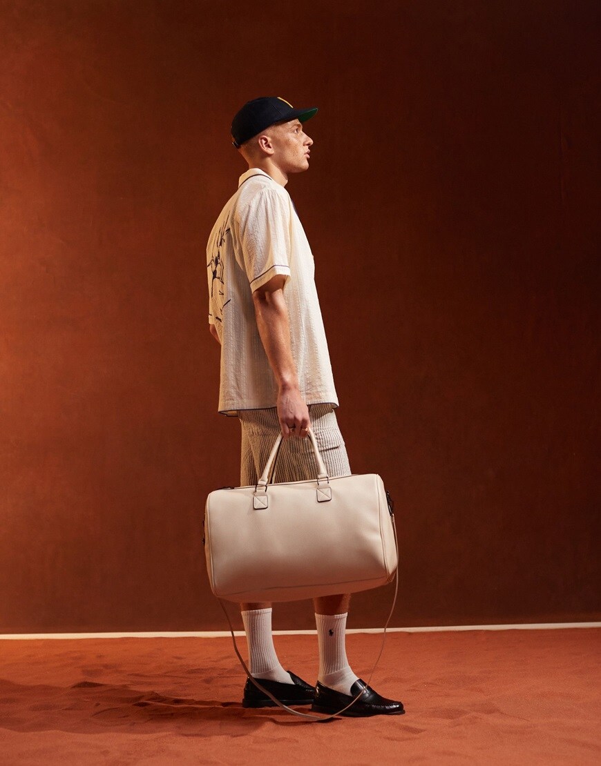 Person holding ASOS DESIGN faux leather holdall in ecru