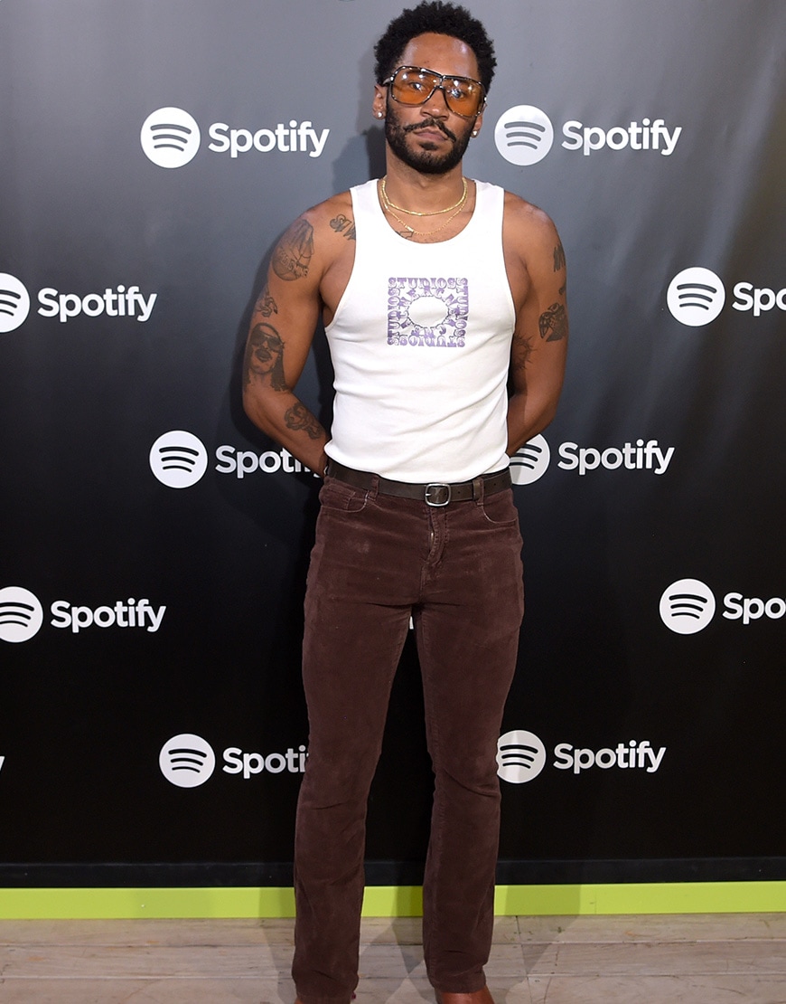 Kaytranada in a vest and brown trousers