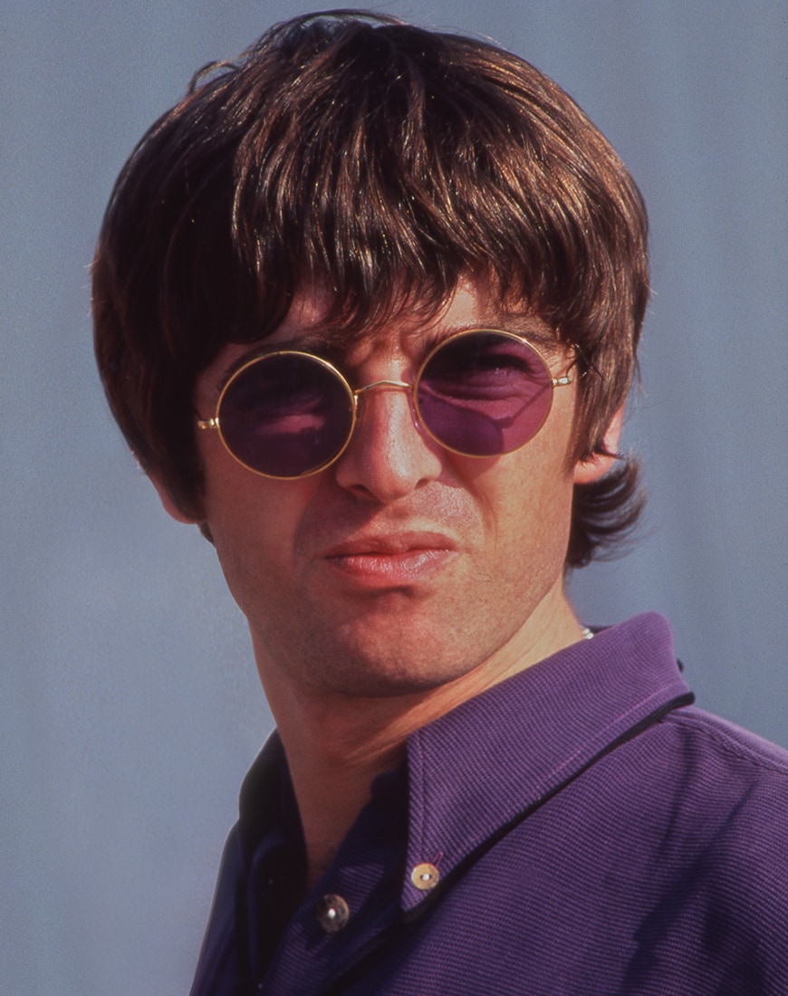 Noel Gallagher wearing round purple tinted sunglasses