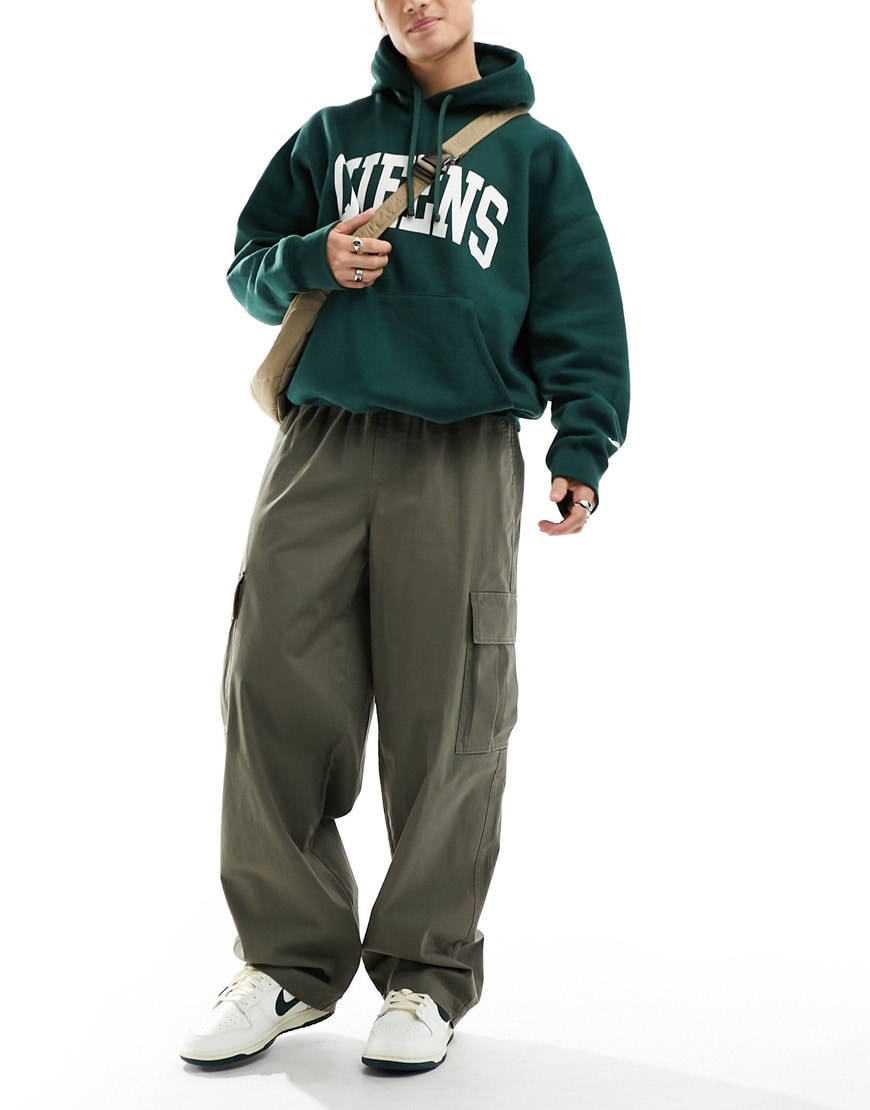 Model wearing green slogan hoodie with khaki cargo pants