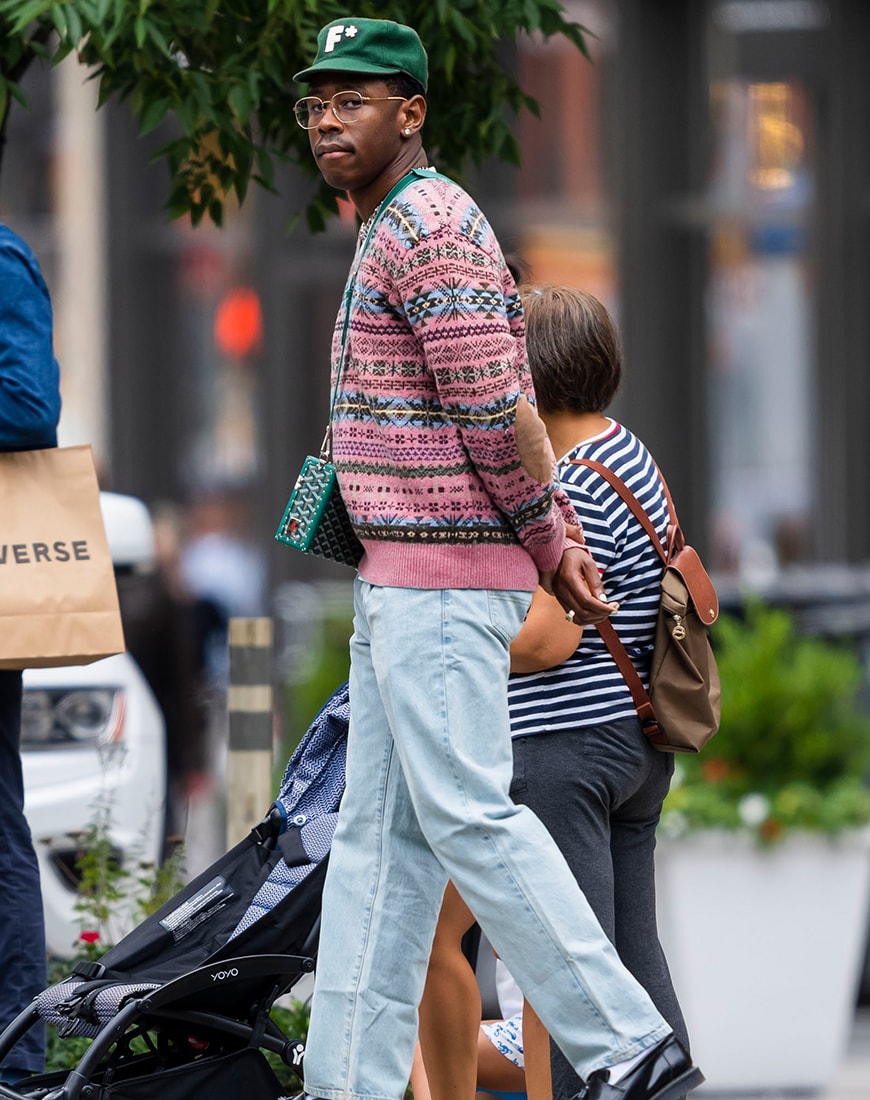 Tyler, the Creator wearing green cap, knitwear and denim trousers